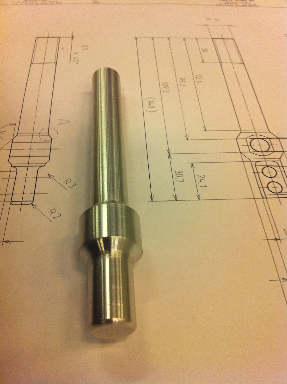 Machined shifter part lying on its technical drawing
