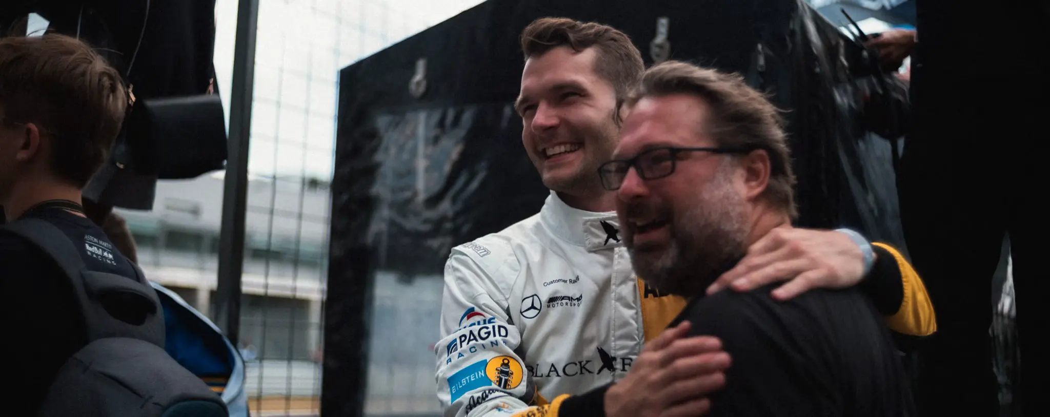 Two men laughing together in the paddock after a session
