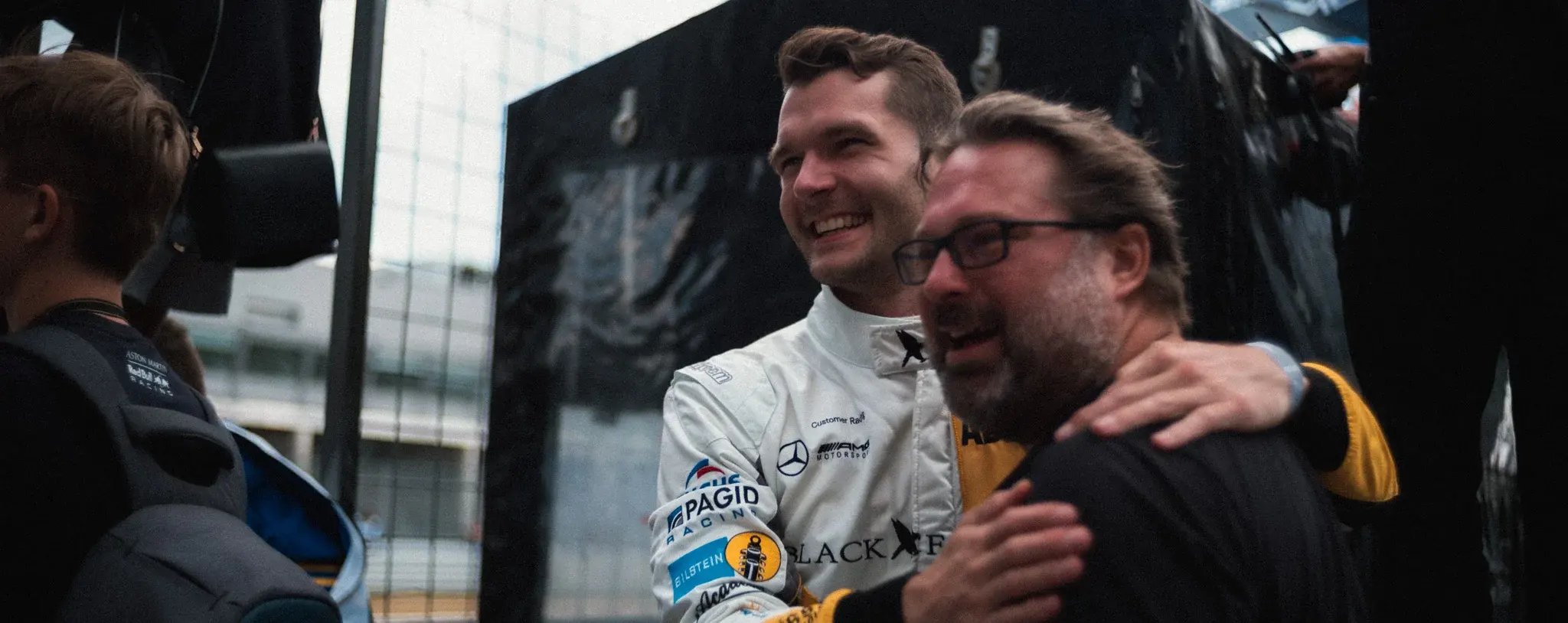 Two men laughing together in the paddock after a session